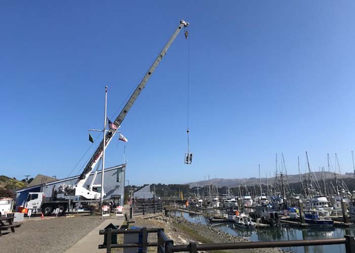 Large crane moving an electrical box in the marina